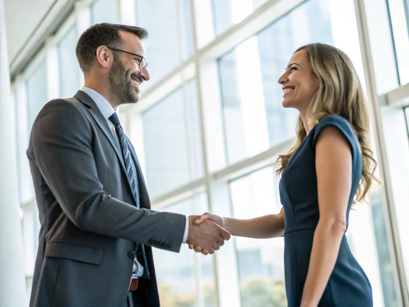 A professional headshot of a Bronco Safari event attendee shaking hands with a representative from a sponsoring company, set against the backdrop of the event's vendor area.